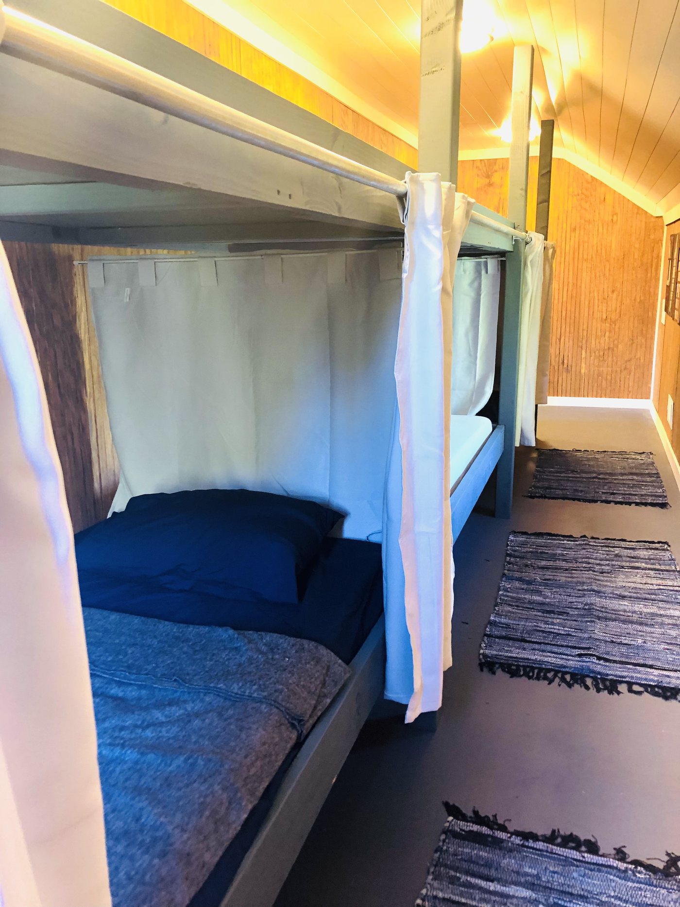 Curtained bunkhouse sleeping space with individual beds, inspired by a sleeper train