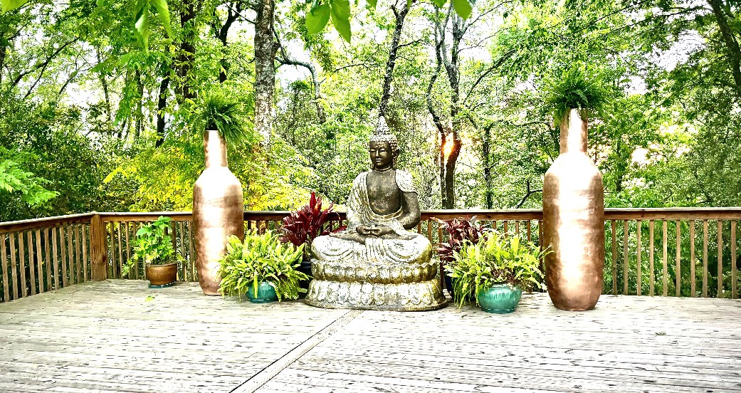 Buddha statue and copper vases on the wooded meditation deck at Golden Hill Retreat Center